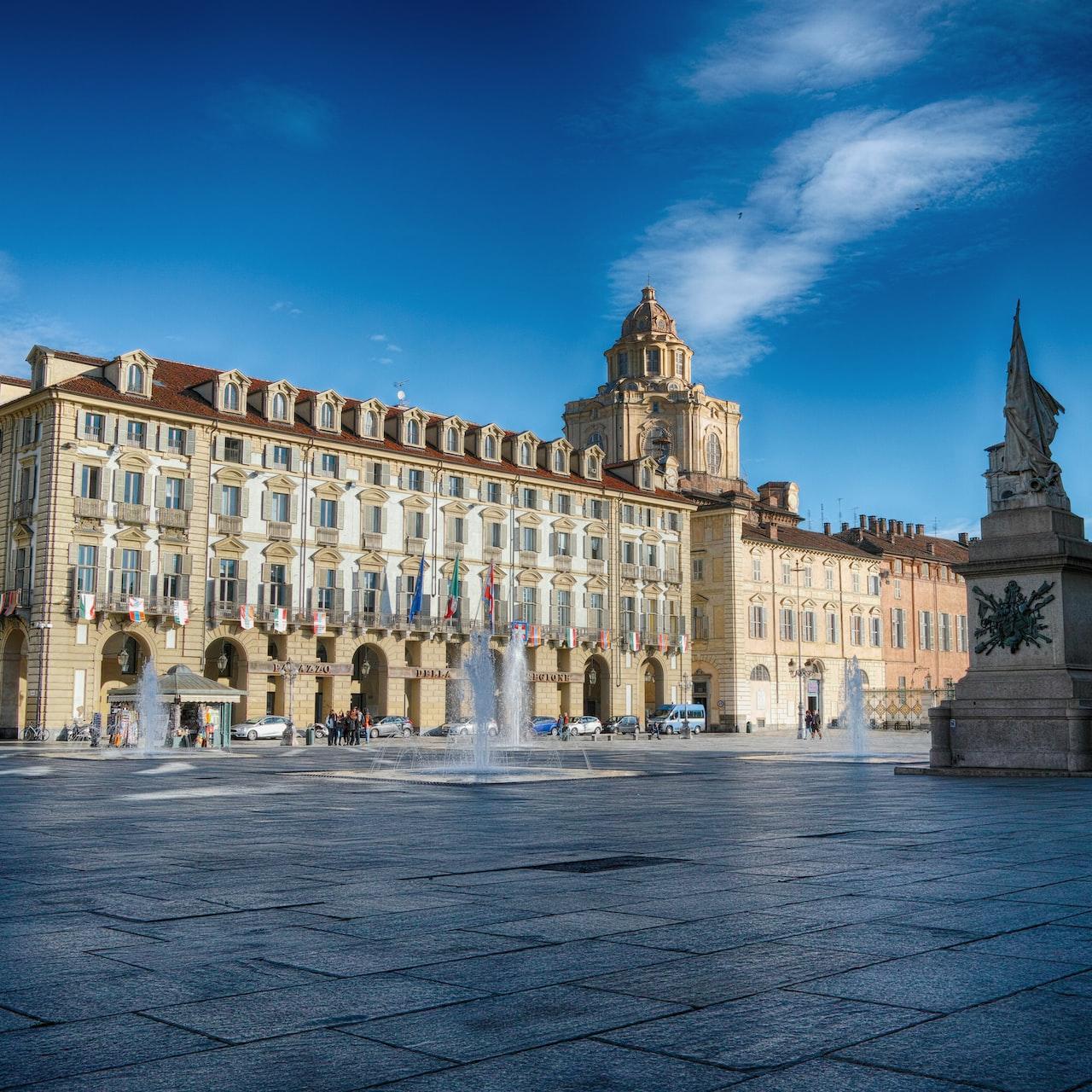 beige concrete palace with statue in front under blue sky at daytime